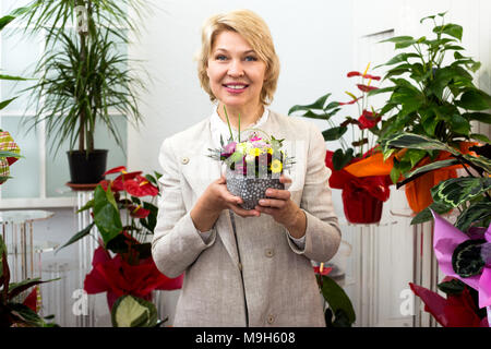 Portrait ältere Frau lächelnd unter bunten Blumen Blumengeschäft Stockfoto