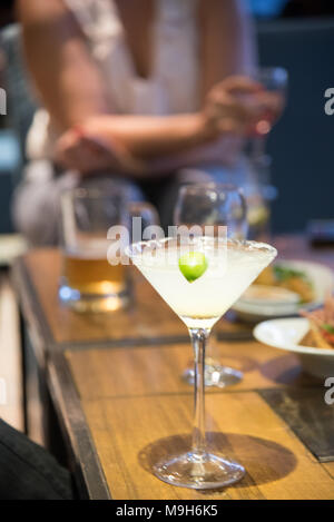 Eine margarita Drink sitzt auf einem Tisch im Fokus. Im Hintergrund sind eine Vielzahl von alkoholischen Getränken wie Bier und Wein. Stockfoto