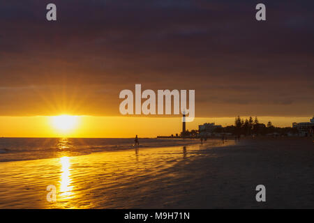 Walker am Strand mit Leuchtturm bei Sonnenuntergang in Maspalomas, Gran Canaria. Stockfoto