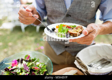 Nicht erkennbare Mann mit einem Teller mit Essen. Familie Feier draußen im Hinterhof. Big Garden Party. Stockfoto