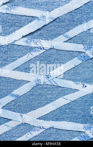 Dünne Streifen geschnitten aus feinem Tuch, auf Blue Denim in geometrischen rhombischen aufgenäht. Stockfoto