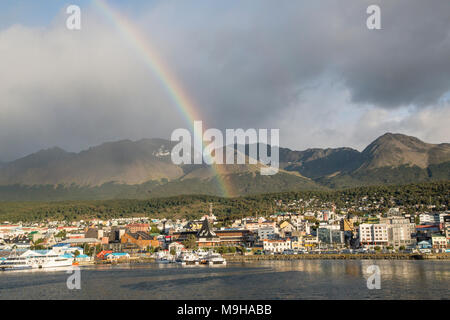 Blick über Ushuaia Hafen und Stadt, mit Anden im Hintergrund und Regenbogen über dem Hafen Stockfoto