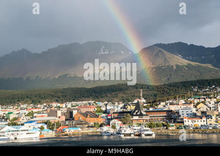 Blick über Ushuaia Hafen und Stadt, mit Anden im Hintergrund und Regenbogen über dem Hafen Stockfoto