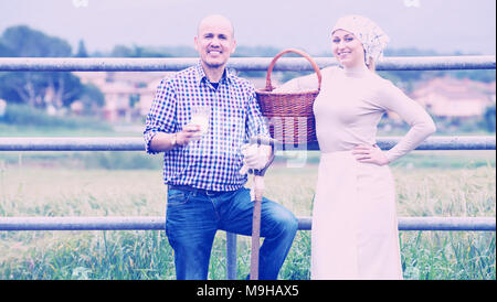 Portrait älterer Mann und junge Frau zu Plaudern und Genießen Milch neben metallischen Zaun im Freien Stockfoto