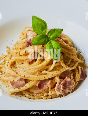Spaghetti Carbonara auf weißem palte mit Basilikum Blatt Stockfoto
