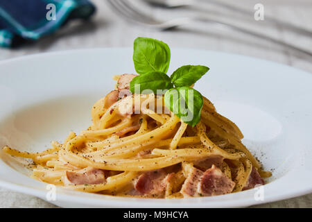 Spaghetti Carbonara auf weißem palte mit Basilikum Blatt Stockfoto