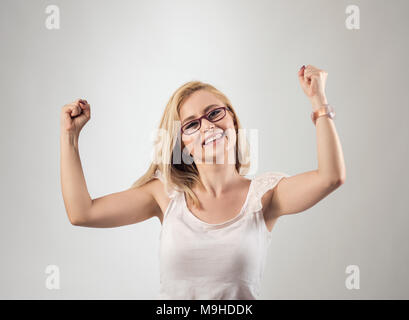 Portrait von Frau frohlockt pumpen Fäuste ekstatisch feiert Erfolg gegen grauen Hintergrund. Stockfoto