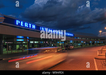 Eine externe Dämmerung Blick auf den Internationalen Flughafen Perth in Western Australia. Ein unscharfer Auto bewegt sich über Rahmen im Vordergrund. Stockfoto