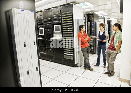 Drei multi-ethnischen Techniker in einem großen Computerraum arbeiten. Stockfoto
