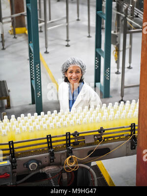 Portrait der afrikanischen amerikanischen Arbeiterin Tragen eines Net und in der Nähe von einem Förderband der Zitrone Flavoured Water in einer Abfüllanlage. Stockfoto