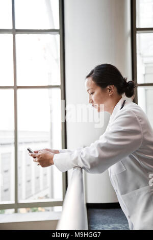 Asiatische Frau Doktor texting. Stockfoto
