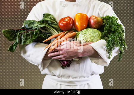 Nahaufnahme der Chef mit seinen Armen voller frisch gepflückte Gemüse. Stockfoto