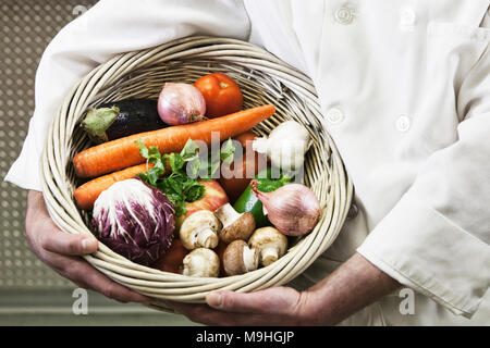 Koch Holding einen Korb mit frisch gepflückten Gemüse. Stockfoto