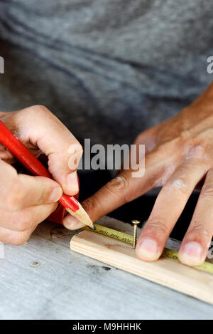 Nahaufnahme eines jungen kaukasischen Mann, eine Markierung mit einem Zimmermann Bleistift in einen Wald streifen Stockfoto