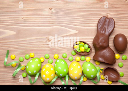 Ostern Eier, Schokolade Osterhasen, Bonbons und Farbband auf Holz- Hintergrund. Stockfoto