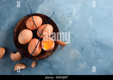 Eigelb in eine Eierschale close-up. Rohe Zutaten zum Kochen Hintergrund mit kopieren. Moderne Ostern Konzept mit braunen Hühnereier Stockfoto