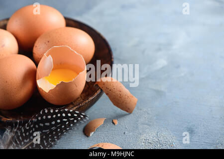 Eigelb in eine Eierschale close-up. Rohe Zutaten zum Kochen Hintergrund mit kopieren. Moderne Ostern Konzept mit braunen Hühnereier Stockfoto