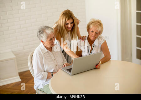 Portrait von glücklichen Frauen aus drei Generationen mit Laptop im Zimmer zu Hause. Stockfoto