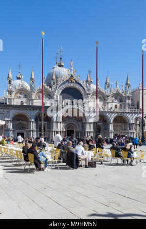 Leute genießen Mittagessen in Piazza San Marco (Markusplatz), Venedig, Italien vor der Basilika San Marco (Markusplatz Basilika) auf einem sonnigen blauen Himmel Tag Stockfoto