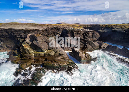 Wellen gegen die Klippen auf der Nordseite von Valentia Island, County Kerry, Irland Stockfoto