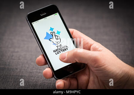 Ein Mann mit der Nationalen Lotterie App auf dem iPhone Stockfoto