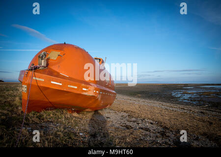 Eine alte, verlassene, orange Leben Boot links am Strand zwischen Rampside und Roa in der Nähe von Barrow-in-Furness, Cumbria. Stockfoto