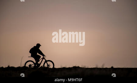 Ein Mountainbiker gegen den Abendhimmel in Cumbria. Stockfoto