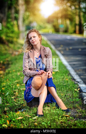 Nachdenkliche Frau sitzt auf einem Koffer Stockfoto