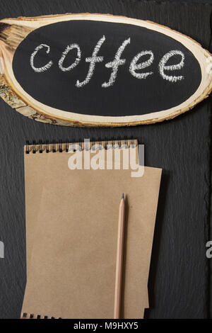 Typenschild aus einer Birke Board mit dem Text 'Kaffee' auf einem schwarzen Brett. Bild mit Platz für Ihren Text, Rezeptur oder Menü. Ansicht von oben. Stockfoto