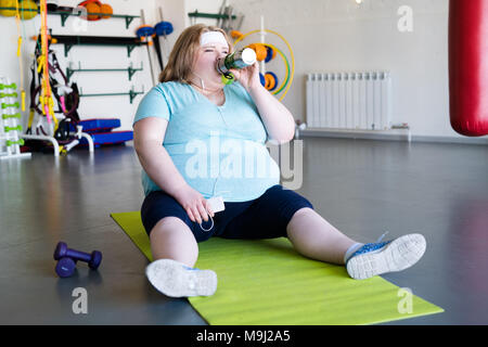 Beleibte Frau Trinkwasser nach dem Workout Stockfoto