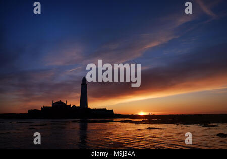 Die Sonne geht hinter der St Mary's Leuchtturm, Whitley Bay in Tyne und Wear. Stockfoto