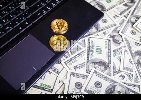 Bitcoins und Dollar auf einem Laptop auf einen hölzernen Tisch. E-Commerce und der Währung. Stockfoto