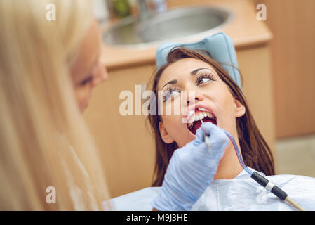 Schöne junge Frau zu Besuch beim Zahnarzt Büro- und Zahnarzt reparieren ihre Zähne. Stockfoto