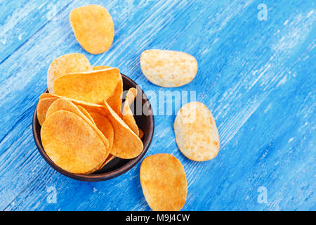 Knusprige Kartoffelchips in einem Steingut Teller auf Blau Küchentisch Stockfoto