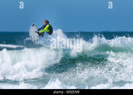 Ein Surfer eine spektakuläre Luftaufnahmen Trick von der Spitze einer Welle an Fistral in Newquay Cornwall. Stockfoto