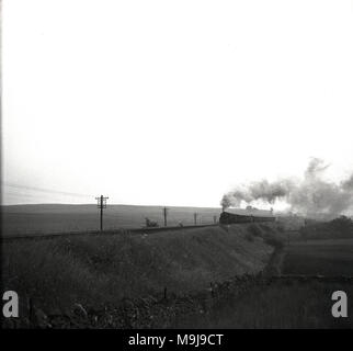 1950, historische, ein Bild von einer Dampflok und Waggons auf einem Bankkonto des ländlichen Eisenbahnlinie, England, UK. Stockfoto
