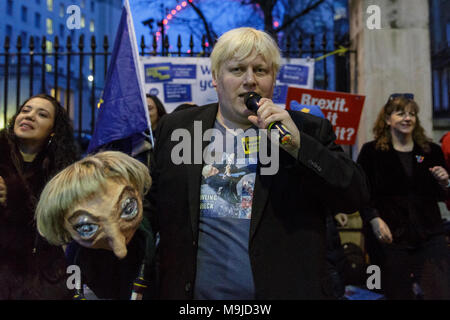 Westminster, London, 26. März 2018. Zeichnete Galdron, als Faux Bojo, Boris Johnson Imitator von London bekannt, tritt in die pro-europäische, Anti-Brexit Demonstranten vor Downing Street für einen Abend singalong mit seinem Theresa May Marionette. Credit: Imageplotter Nachrichten und Sport/Alamy leben Nachrichten Stockfoto