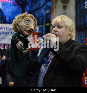 Westminster, London, 26. März 2018. Zeichnete Galdron, als Faux Bojo, Boris Johnson Imitator von London bekannt, tritt in die pro-europäische, Anti-Brexit Demonstranten vor Downing Street für einen Abend singalong mit seinem Theresa May Marionette. Credit: Imageplotter Nachrichten und Sport/Alamy leben Nachrichten Stockfoto