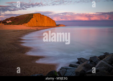 West Bay, Dorset, Großbritannien. 26. März, 2018. UK Wetter: Die Heimat des Broadchurch und Harbour Lights ist in einer unglaublichen goldenen Glanz leuchtet wie die Sonne auf die Küstenstadt setzt. Nach einem Wochenende von trübes Wetter, die ikonische Fischereihafen ist in warmes Licht vor einem Zauber von nassem Wetter bewegt sich über dem Land von Dienstag an gebadet. Credit: Wayne Farrell/Alamy Nachrichten Stockfoto