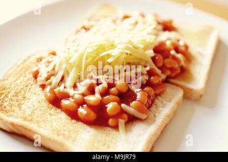 Gebackene Bohnen auf Toast überbacken mit Geriebener Cheddar-Käse Stockfoto