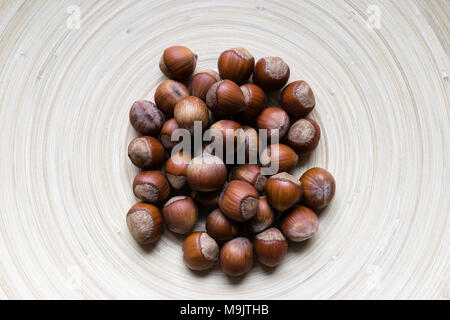 Gruppe der ganze Haselnüsse auf weichem Braun Bambus platte Hintergrund Oberfläche Stockfoto