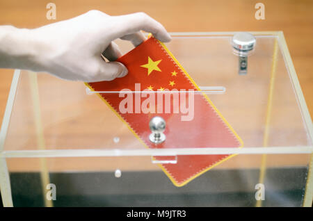 Mann einfügen Flagge von China in die Wahlurne, Abstimmungen und Wahlen in China. Stockfoto