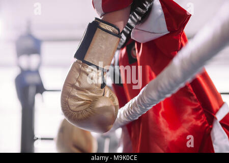 Seitenansicht der Sportlerin in rot Sportswear hängenden gelben Boxhandschuhe am Seil der Ring. verloren kämpfen. gebunden Fighter Stockfoto