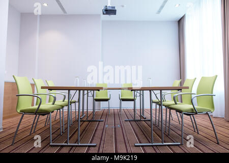Seitenansicht der Tabelle mit leeren invertiert Gläser und Grünen moderne Büro chaires Stockfoto