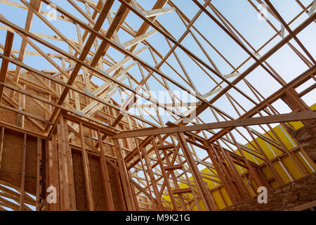 Neue Bau home Framing gegen den blauen Himmel, Nahaufnahme der Decke. Holz Gebäude frame Struktur auf eine neue Entwicklung website Stockfoto