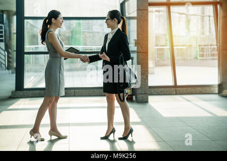 Zwei asiatische business Frauen treffen sich in der modernen Gesellschaft und ihre Hände schütteln. Auf der Seite anzuzeigen. Zusammenarbeit Konzept. Sie haben ein Erfolg Partner Ship. Stockfoto