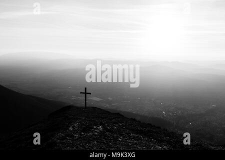 Kreuz auf dem Gipfel des Mt. Serrasanta (Umbrien, Italien), mit Sun niedrig am Horizont Stockfoto