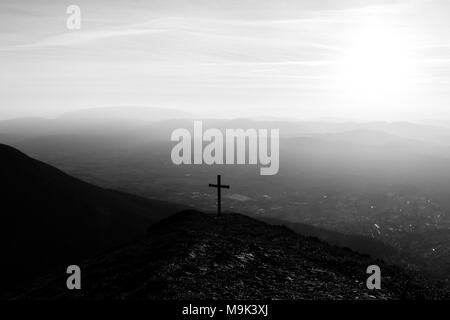 Kreuz auf dem Gipfel des Mt. Serrasanta (Umbrien, Italien), mit Sun niedrig am Horizont Stockfoto