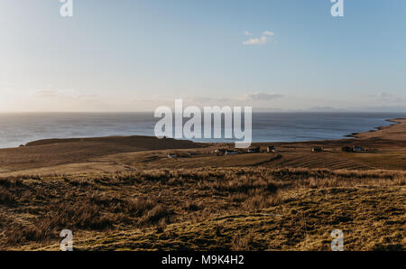 Blick auf die Landschaft und ein kleines Dorf an der Küste auf der Insel Skye, Schottland, während der Goldenen Stunde. Stockfoto