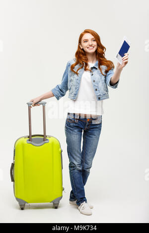Reisen und Lifestyle: Porträt von einem aufgeregten Jungen kaukasischen Frau im Sommer Kleidung holding Passport mit fliegenden Karten beim Stehen mit einem Koffer über hellen gelben Hintergrund gekleidet Stockfoto